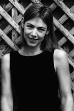 This black and white photo of the poet Olena Kalytiak Davis shows a young woman in front of a garden lattice. 