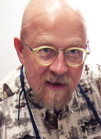 this is a photo of author Anton Rajer, at work on a conservation project. He is bearded, wearing glasses, and wears a blue work apron over his shirt.